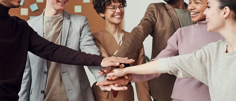 Mehrere Personen in Arbeitskleidung die ihre Hände aufeinander legen&nbsp;&copy;&nbsp;fauxels / pexels