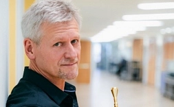 Andy Haderer lehnt sich an eine Wand und hält eine Trompete in den Händen