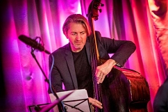Portrait Peter Tümmers Peter Tümmers während er vor einem lila Hintergrund Chello spielt